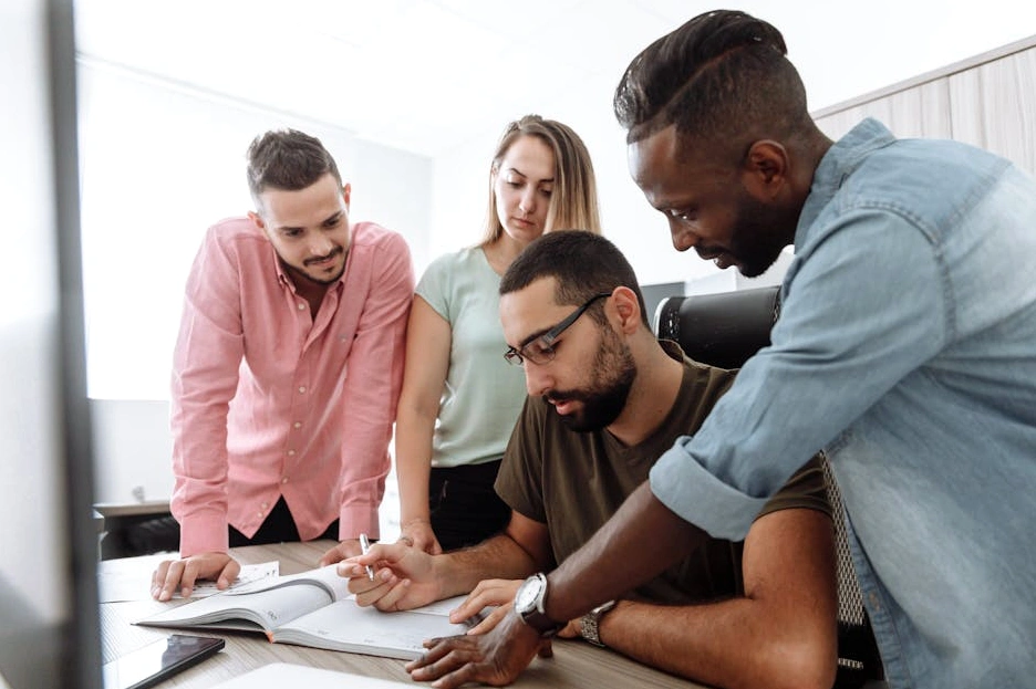 Un team diversificato e sorridente collabora attorno a un tavolo in un ufficio moderno.